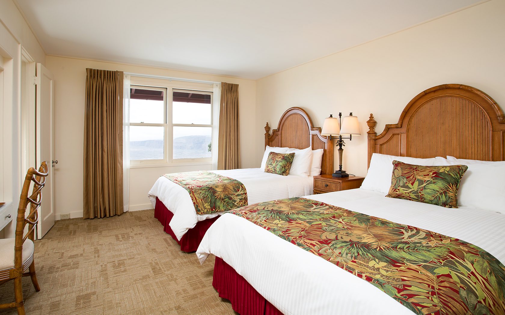 A hotel room with two twin beds, wooden headboards, and a window with a view.
